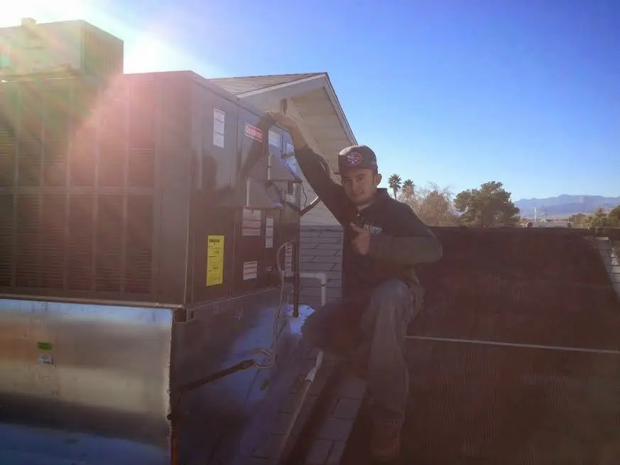 HVAC technician performing HVAC Inspection on a rooftop unit in Cohasset